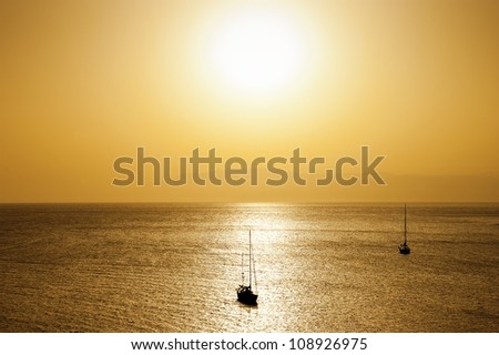 Two boats in the sea during a golden sunset, setting sun over the Mediterranean Sea