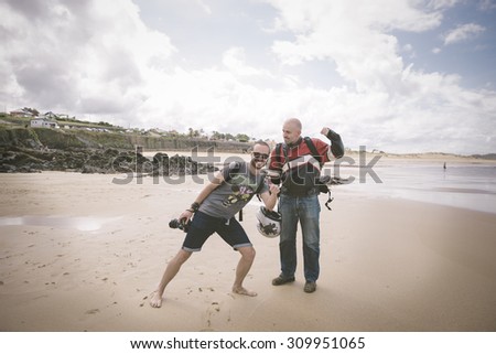 Strange friends on the beach; photographer is smiling and biker is getting ready to punch the photographer.