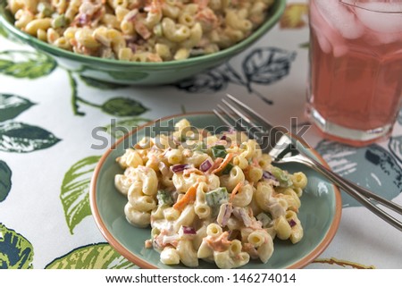 A serving of traditional elbow macaroni salad is served with a refreshing glass of cold pink lemonade.