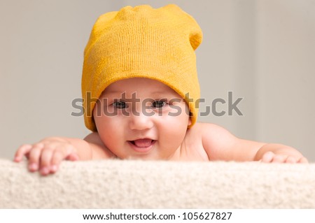 Baby With A Beanie Hat Behind A Sofa