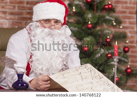 Santa Claus writes a list on the background of the Christmas tree