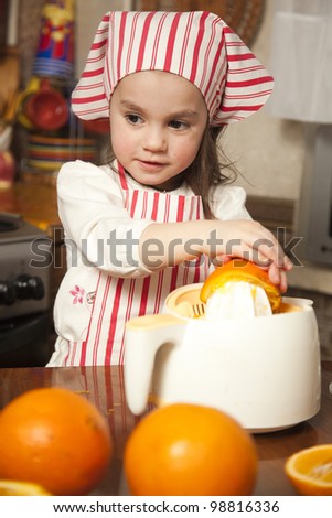 Little girl making fresh and healthy orange juice with kitchen appliance