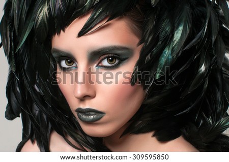 Beautiful model woman face closeup. Mysterious girl portrait\
feathers hairstyle.