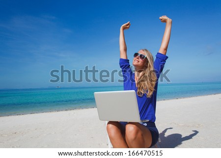 Beautiful young woman working with laptop on the tropical beach