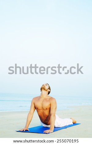 Long Hair Athletic Man with No Shirt doing Yoga on Blue Mat at the Beach\
URDHVA MUKHA SVANASANA - UPWARD FACING DOG POSTURE