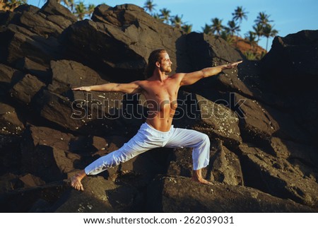 Long Hair Athletic Man with No Shirt doing Yoga on the Rocks