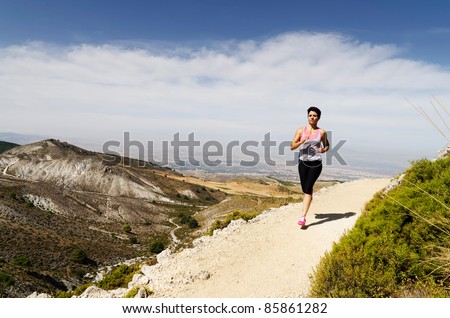 Young short-haired woman  running on a dry mountain path.