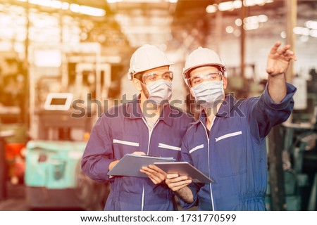 Engineer teamwork worker wearing disposable face mask or face shield during working in factory to prevent Covid-19 virus air dust pollution and for good hygiene. Foto stock © 