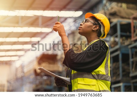 Black African professional women worker working count checking inventory production stock control in business factory  industry warehouse waring engineer suit and helmet for safety