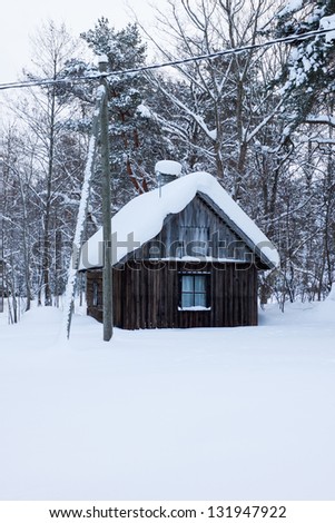 Small wooden forest house covered by snow