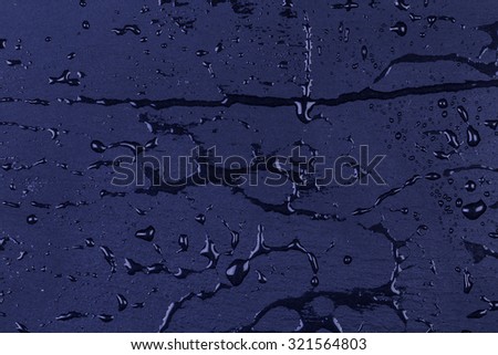 Water drops on blue dark stone surface of basalt or granite