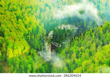 Clouds above deep canyon and mountain forest around it.