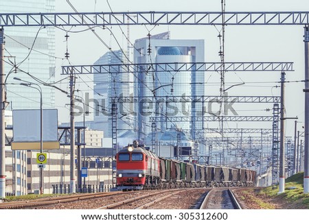 Freight train moves on the business city center in the evening.
