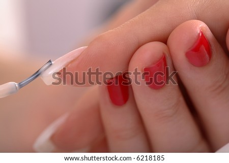 Female painting her fingernails with red polish