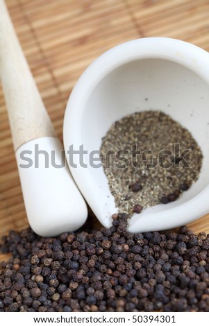 Mortar and pestle grinding up black pepper.