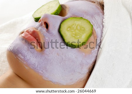Spa girl with beauty mask and cucumbers on her eyes.