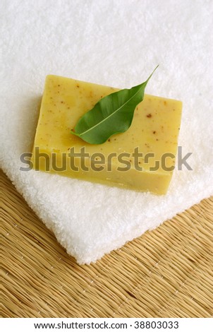 Aromatic soap with green leaf on white folded towel