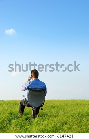 A manager sitting on a chair in nature an do a phone call with his cellphone