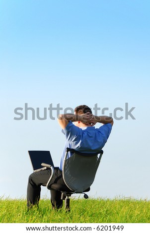 A relaxed manager on a chair in nature with a notebook on his legs