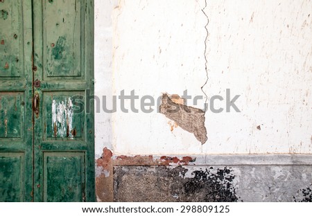 Cracked wall and aged green door on street