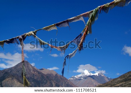 Prayer Flags in Manang - prayer flags strung against an azure blue sky, near Manang along the Annapurna Circuit. Prayer flags promote peace, compassion, strength, and wisdom, in Tibetan Buddhism.