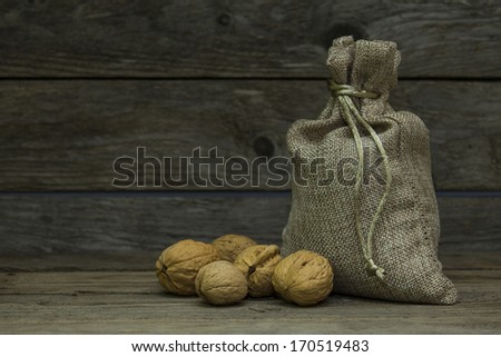 Walnuts in burlap bag on wooden background