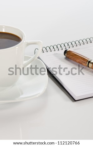 Cup of coffee, pen and notebook on white background detail