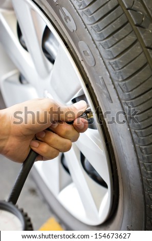 Man\'s hand checking tyre pressure.