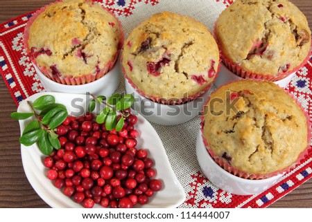 Freshly baked cranberry  muffins with dish of cranberries.