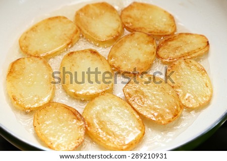 Sliced potatoes fried in a pan with ceramic coating.