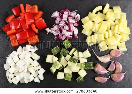 Colored peppers and onions diced on a black board.