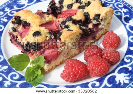 Slice of berry cake and fresh raspberries on a decorative porcelain plate
