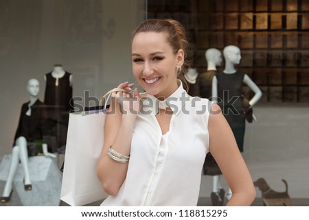 Portrait of young happy woman with shopping bags on the background of shopping mall window