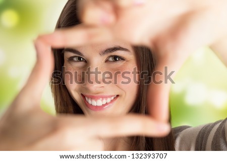 Closeup portrait of young beautiful woman making frame with her hands