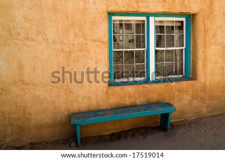 Adobe wall with green window and bench