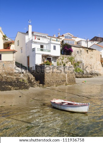 Houses on the sea shore with a boat in the foreground. The photo is taken in a fishing village called \