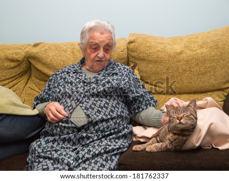 Elderly woman stroking her cat inside home.