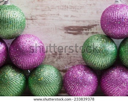 Pink and green christmas balls in a stack over wooden background in a studio shot