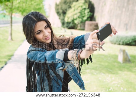 Brunette woman with casual clothing taking a selfie in a park
