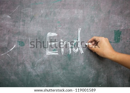 hand with chalk writing \'End\' in the blackboard