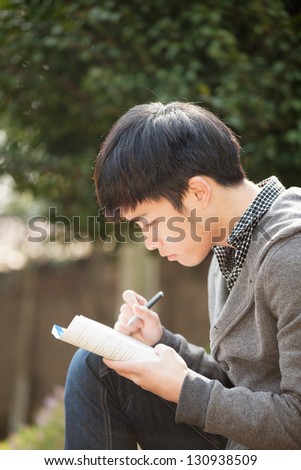 asian male studying in the park
