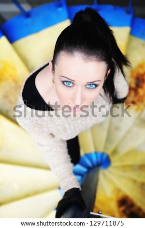 luxury brunette woman with blue eyes looking up posing on a stairs