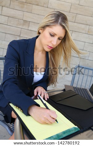 Young pretty business woman writing with a notebook