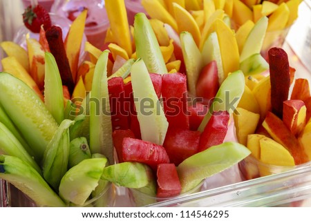 Sliced fruits on cups for sale at a local Farmer\'s Market. A little twist of mexican spicy candy in the mango cups