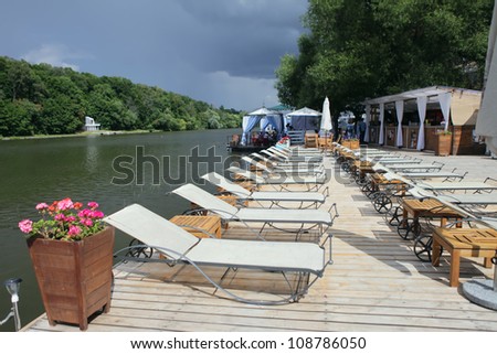 A Lounge chairs on a wooden pier. Moscow river