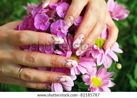 Beautiful nail design. Woman hands with chrysanthemums flowers.