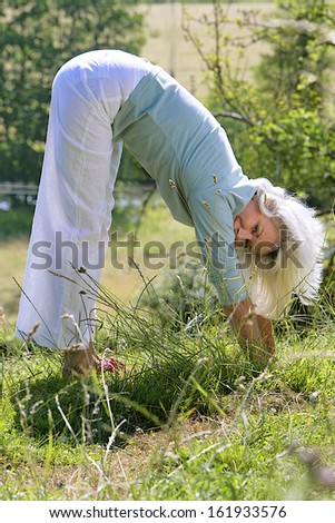 middle aged woman  doing yoga outside in park