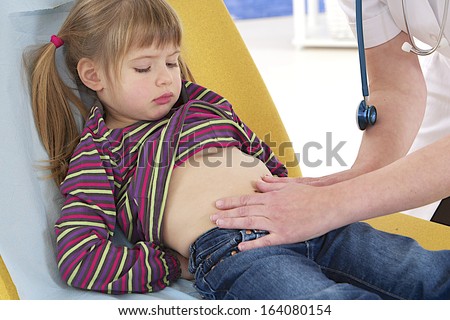doctor touching the painful belly of cute little patient - focus on belly palpation