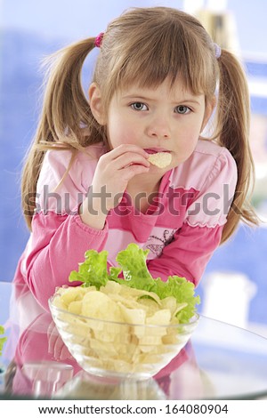 happy little girl eating potato chips and salad