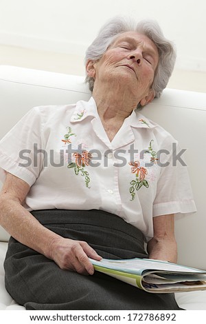 Elder woman falling asleep while reading a book